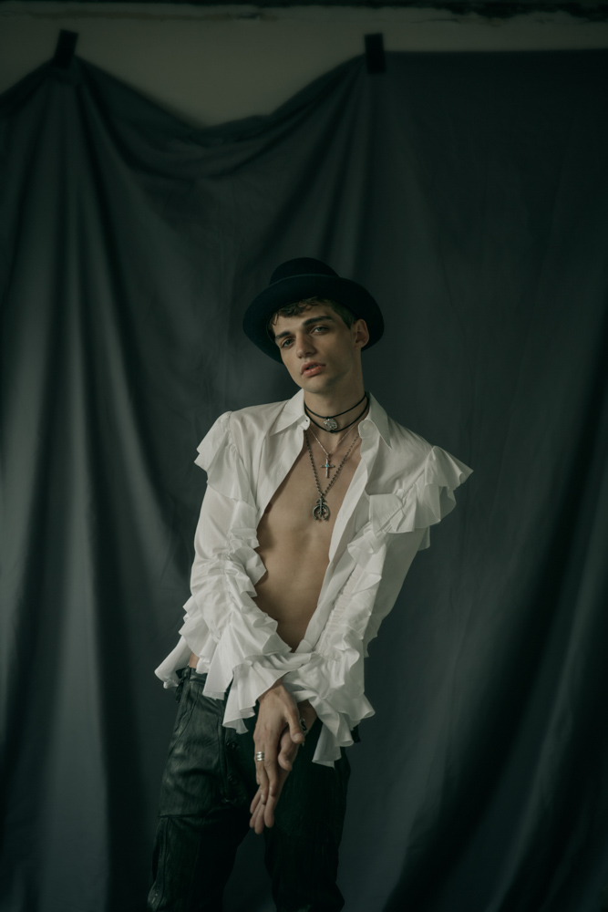 White shirt with ruffles by Viktor&Rolf Leather pants by Sandrine Philippe Hat by Laurence Bossion Cross necklace, sailor wheel necklace by Harpo Gold plated metal, leather necklace from Nature collection by Delphine-Charlotte Parmentier Ring by Harpo 