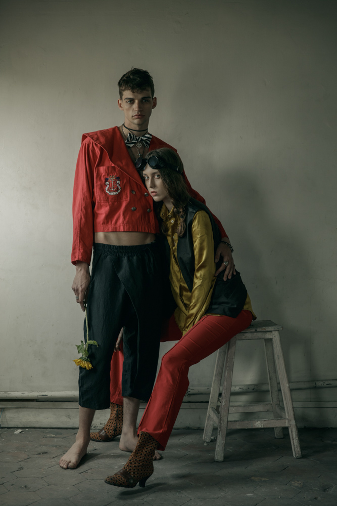 HIM Red vintage cotton jacket - Stylist’s own Black loose trousers by Sandrine Philippe Sailor wheel necklace, cross necklace by Harpo Bowtie by Bowsdontcry Silver plated metal, leather men bracelet from Tribal collection by Delphine-Charlotte Parmentier HER Gold shirt by Coppelia Pique Classic gilet by Hugo Boss Red flare pants - Stylist’s own Hat by Laurence Bossion Necklace, rings by Harpo Boots - Stylist’s own